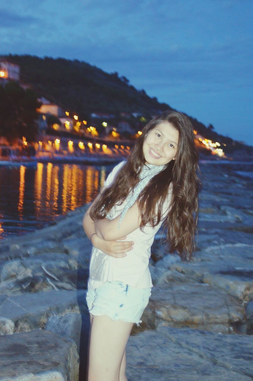 young adult, young women, water, lifestyles, person, leisure activity, looking at camera, long hair, portrait, standing, focus on foreground, front view, casual clothing, sea, three quarter length, smiling, sky