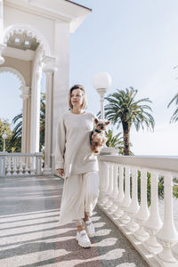 Blond woman with pet dog walking on balcony