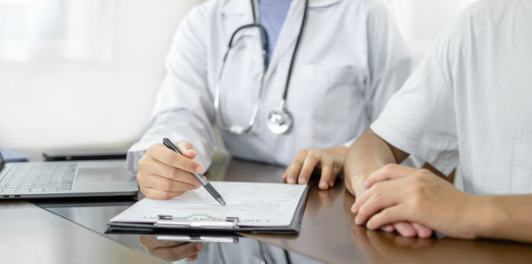 Midsection of doctor examining patient at clinic