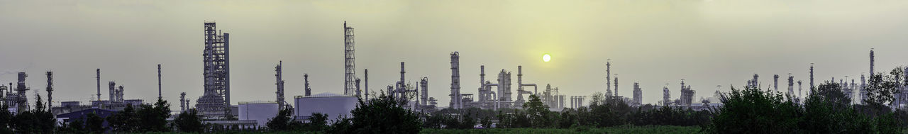 Panoramic view of factory against sky during sunset