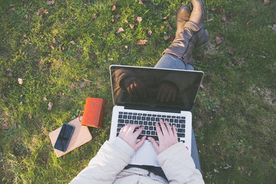 Low section of woman using laptop on grass