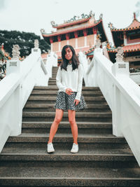 Full length portrait of young woman standing on steps