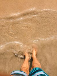 Low section of man standing in sea