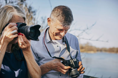 Senior man and woman with cameras at park