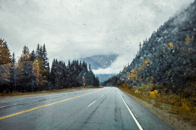 Road by mountains against sky during rainy season