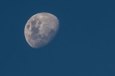 Low angle view of moon against clear blue sky