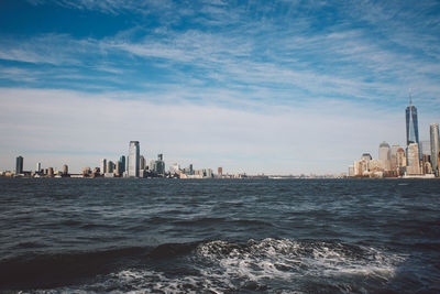 Sea by cityscape against sky