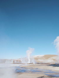 Smoke emitting from volcanic landscape against sky