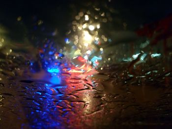 Close-up of water drops on illuminated lights
