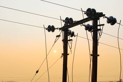 Low angle view of silhouette birds on electricity pylon against sky