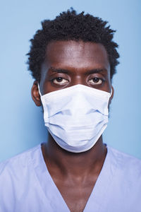 Portrait of man wearing mask against blue background