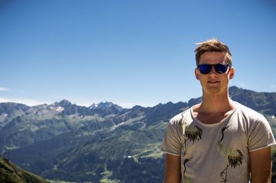 Man wearing sunglasses standing on mountain against clear sky