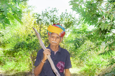 A wooden tool on the shoulder of an indian aged farmer with the help of which the thorns scattered 