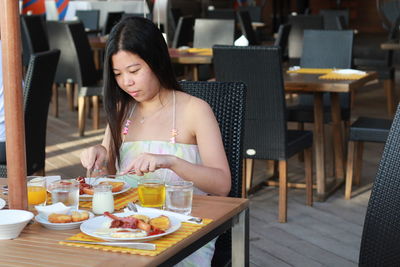 Asian woman sitting and eating breakfast in restaurant
