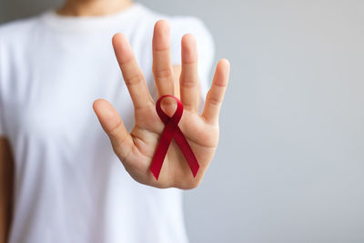 Midsection of woman holding ribbon against white background