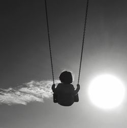 Low angle view of child on swing at playground