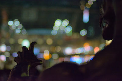 Close-up of hands on illuminated city at night