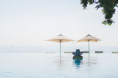 Rear view of young woman in infinity pool against sea