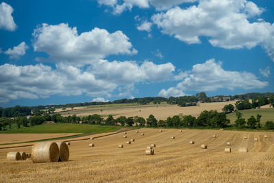 Hay bales on field against sky