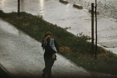 Woman walking on footpath in city during snowfall