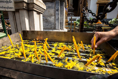 Cropped image of hand offering candles at temple