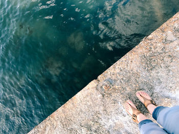 Low section of woman standing on jetty over sea