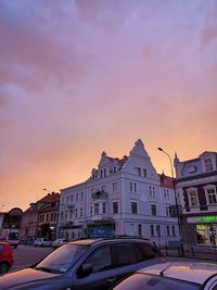 Street by buildings against sky at sunset