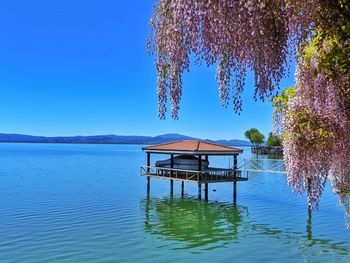 Gazebo in lake against clear blue sky