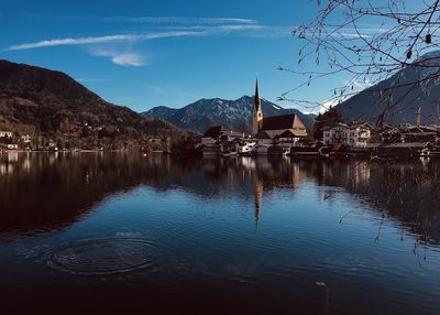 Houses by lake and buildings against sky