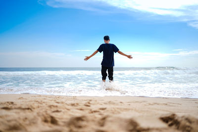 A man in a blue shirt, enjoying the waves on a very clean, beautiful and white sandy beach.