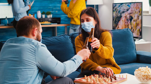 Man and woman drinking beer while playing chess at home