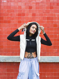 Portrait of young woman standing against wall