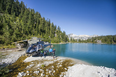 Tourist group arrives at lake via helicopter for adventure tour.