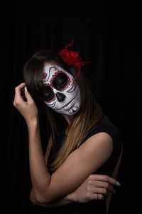 Midsection of woman wearing mask against black background