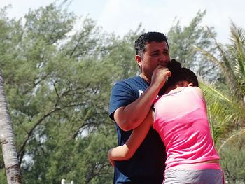 Girl hugging father against trees