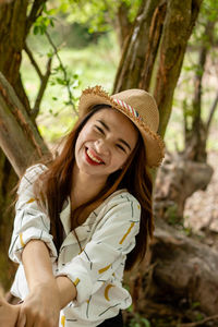 Portrait of smiling young woman by tree