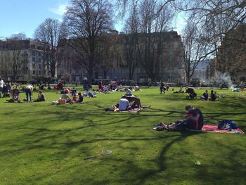 People relaxing on grassy field in park