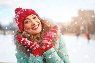 Portrait of smiling young woman wearing knit hat standing outdoors
