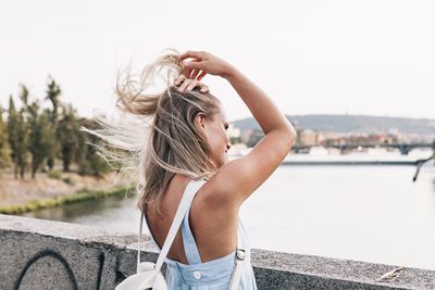 Young woman with tousled hair standing at bridge