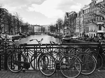 Bicycles by railing against canal amidst buildings