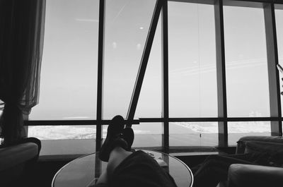 Low section of man sitting by sea against sky