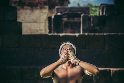 Midsection of shirtless man statue against brick wall