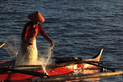 Fisherman fishing on boat in sea during sunset