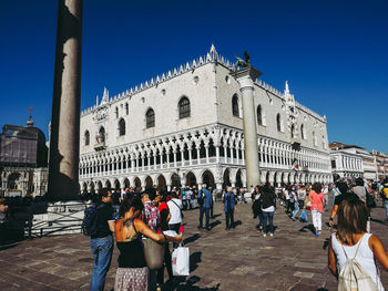 Group of people at historic building against blue sky