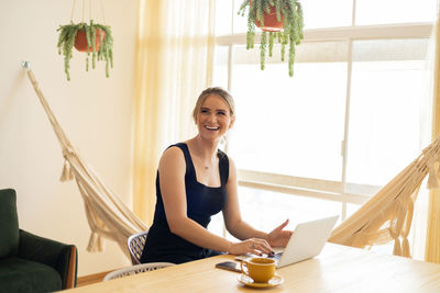 Portrait of young woman using laptop at home