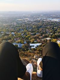 Low section of people sitting in city against sky