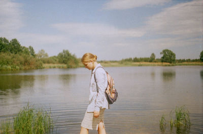 Woman standing by lake against sky