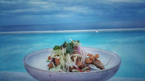 Close-up of food in bowl on table against sea