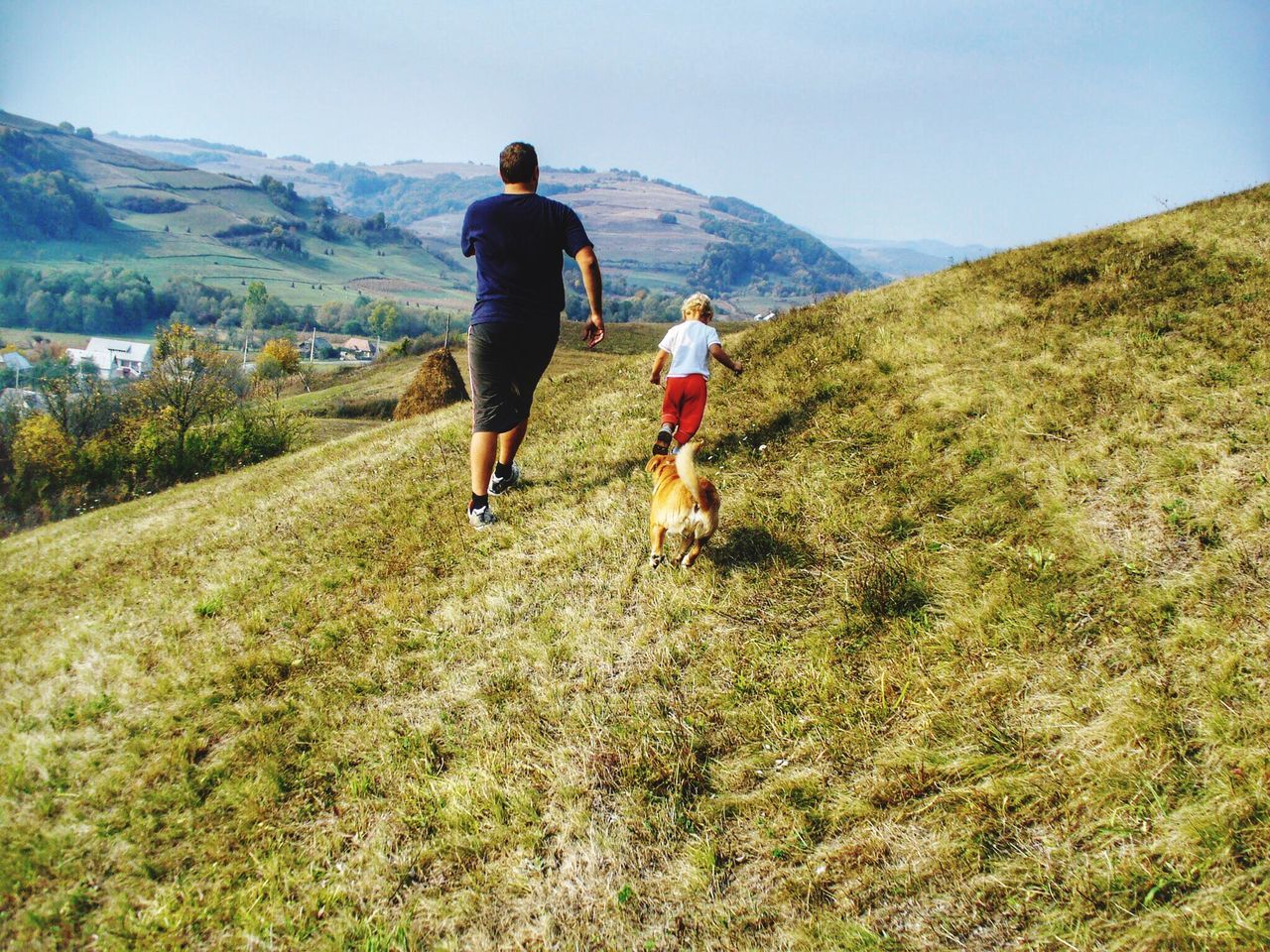 REAR VIEW OF FATHER AND DAUGHTER WALKING ON LANDSCAPE