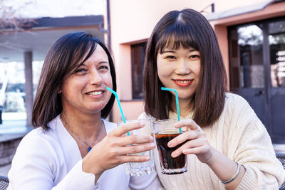 Portrait of smiling young woman drinking glass at restaurant